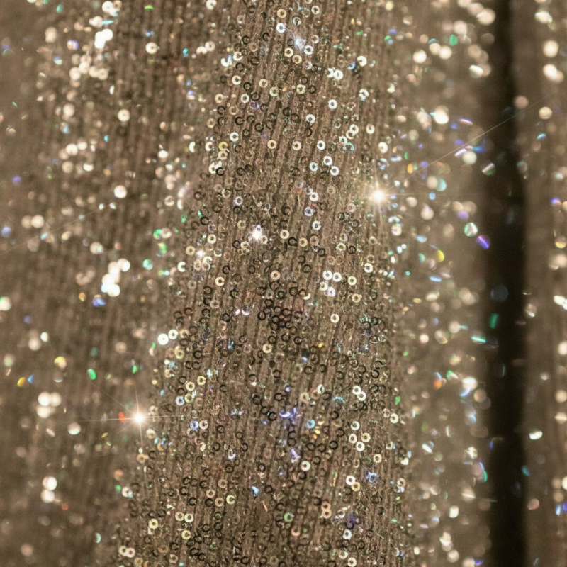 Nahaufnahme des beigen Glitzerstoffs mit feiner, schimmernder Textur und dichter Oberfläche.