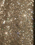 Nahaufnahme des beigen Glitzerstoffs mit feiner, schimmernder Textur und dichter Oberfläche.