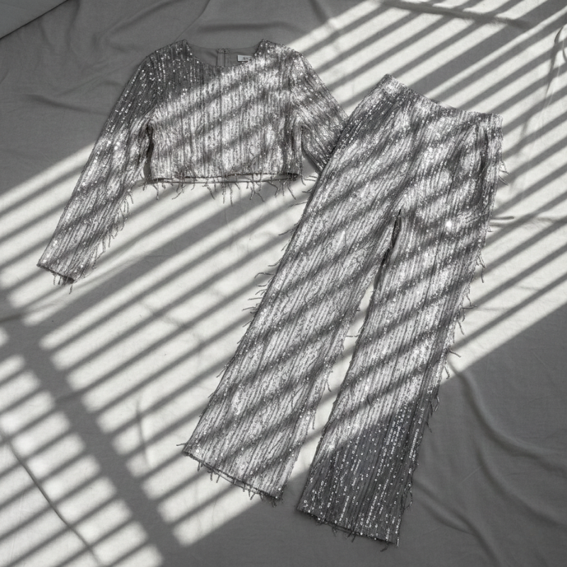 Detailansicht des silbernen Glitzerstoffs mit reflektierender Oberfläche und feiner Webstruktur.