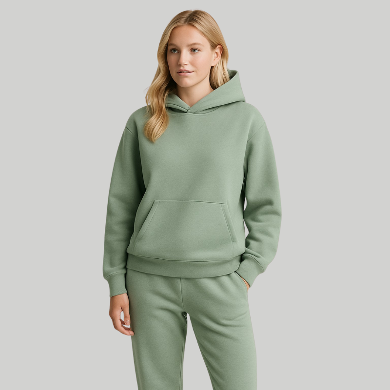 Frau in grünem Hoodie-und-Jogger-Set, aufgenommen von hinten im hellen Studio.