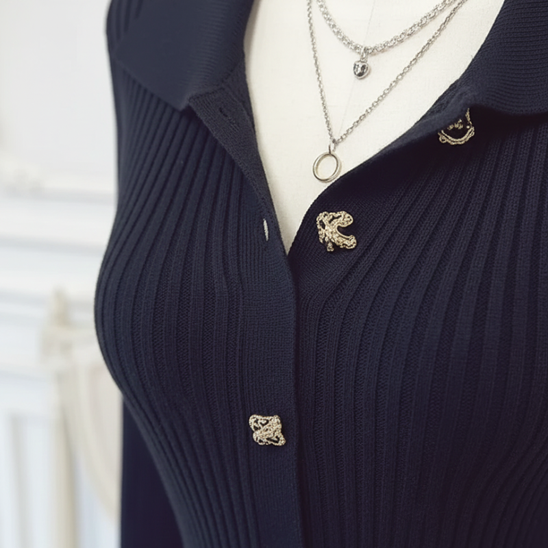 Detailaufnahme der dekorativen Knöpfe an einem schwarzen gerippten Maxi-Kleid