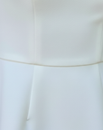 Nahaufnahme des weißen Kleides mit glatter Stoffstruktur und sauberer Verarbeitung im Taillenbereich.
