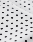 Nahaufnahme eines Stoffes mit Polka-Dot-Muster, der eine glatte Textur und ein klassisches Punktmuster aufweist.