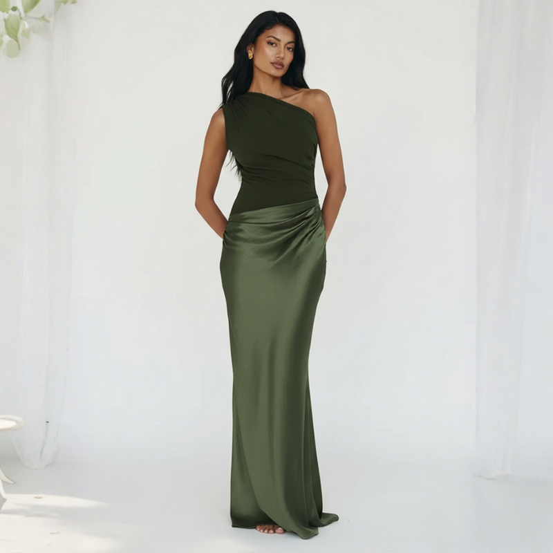 Model trägt ein olivgrünes One-Shoulder-Abendkleid mit elegantem Faltenwurf in einem lichtdurchfluteten Außenbereich.