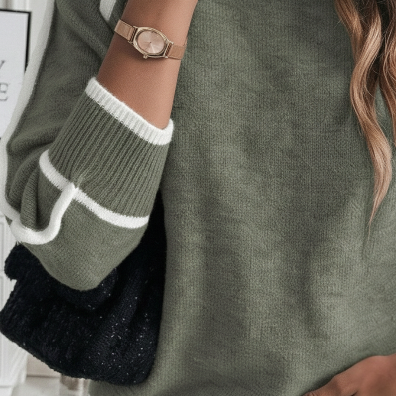 Nahaufnahme des grünen Pullovers mit weicher Strickstruktur und kontrastierenden Ärmelabschlüssen.