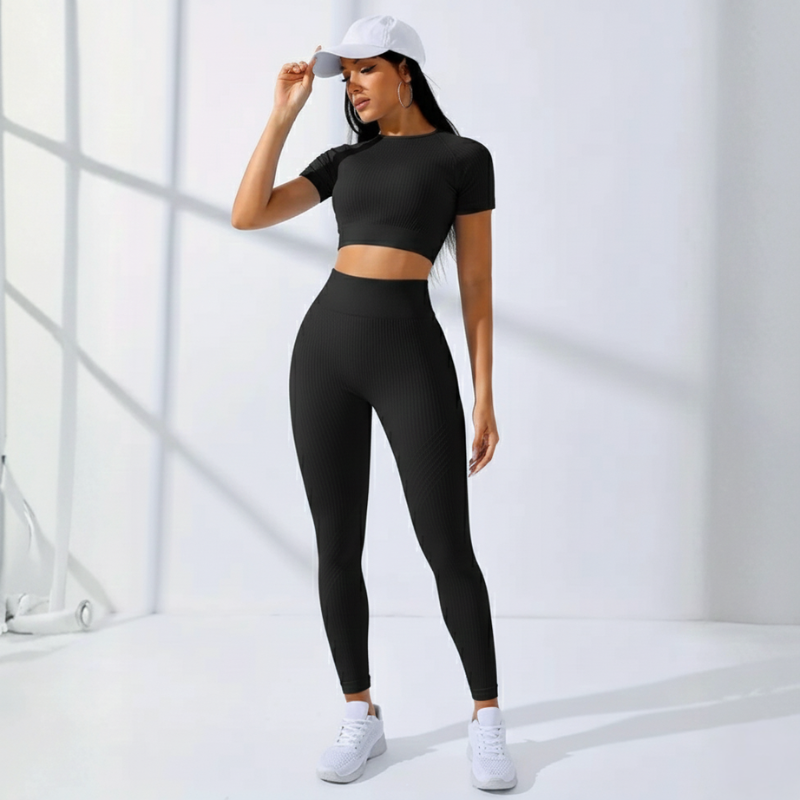 Modell in schwarzem Crop-Top und Leggings vor weißem Studiohintergrund.