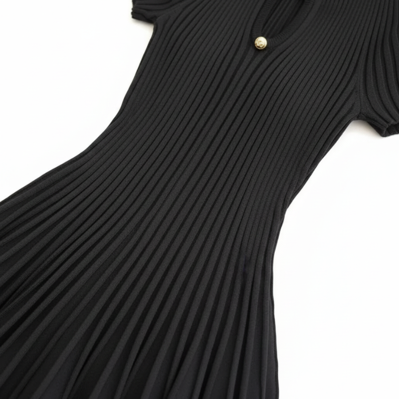 Nahaufnahme des schwarzen plissierten Kleids mit sichtbarer Struktur, feinem Faltenwurf und elegantem Kragen.