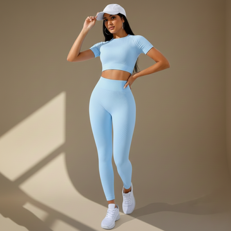 Frau in einem hellblauen Fitness-Zweiteiler posiert im natürlichen Licht.