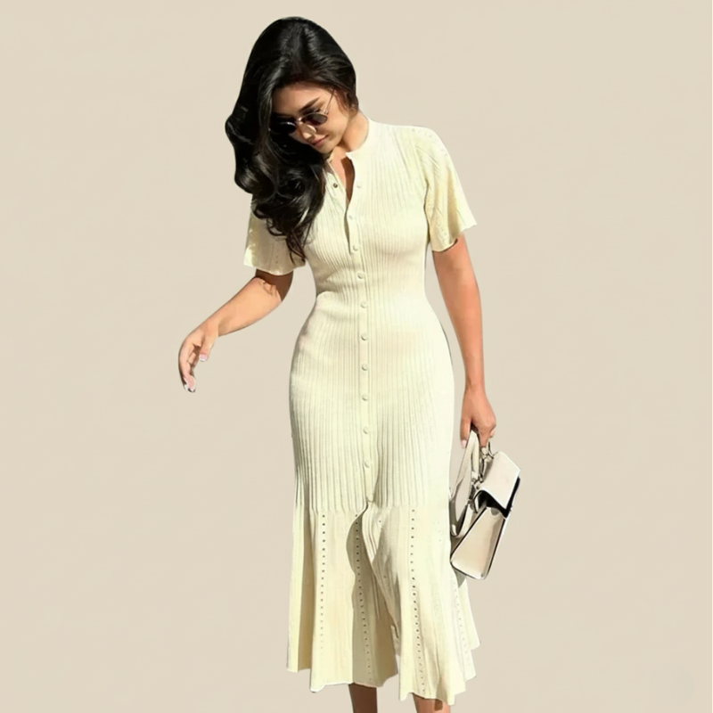 Model präsentiert ein klassisches beiges Strickkleid mit Knopfleiste und strukturierter Oberfläche im minimalistischen Studio.