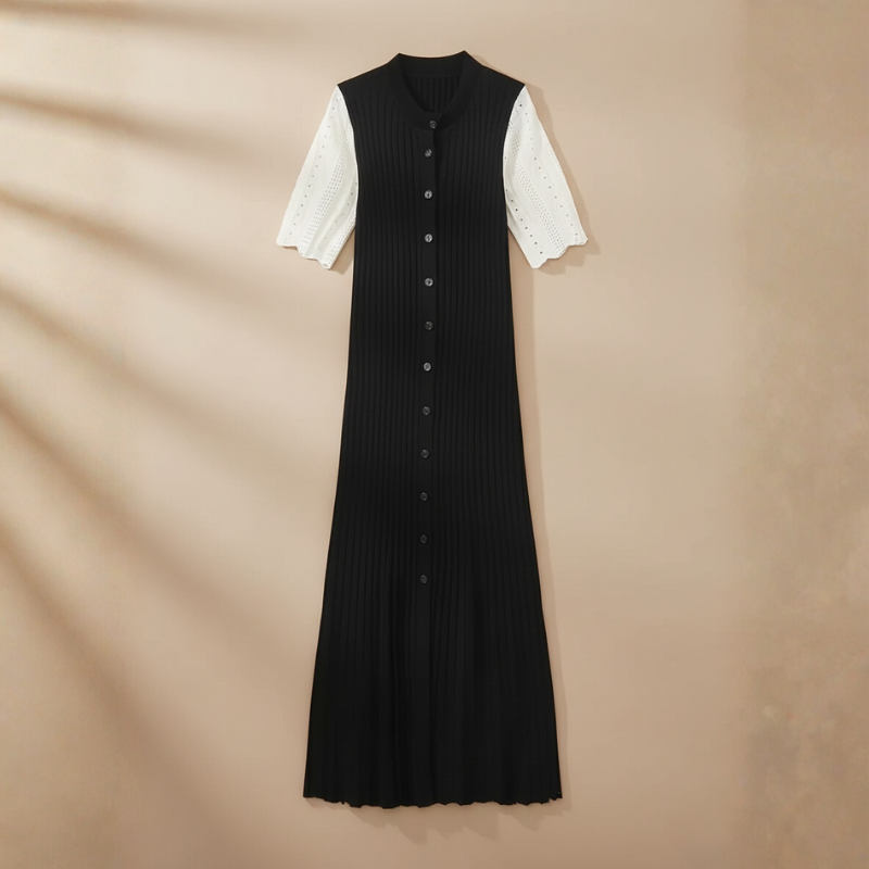 Ärmeloses langes schwarzes Strickkleid mit gerippter Oberfläche auf einem Kleiderbügel vor warmem Hintergrund präsentiert.