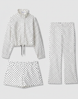 Flach liegendes, weißes, gepunktetes Zweiteiler-Set mit langärmeligem Oberteil und passender Hose