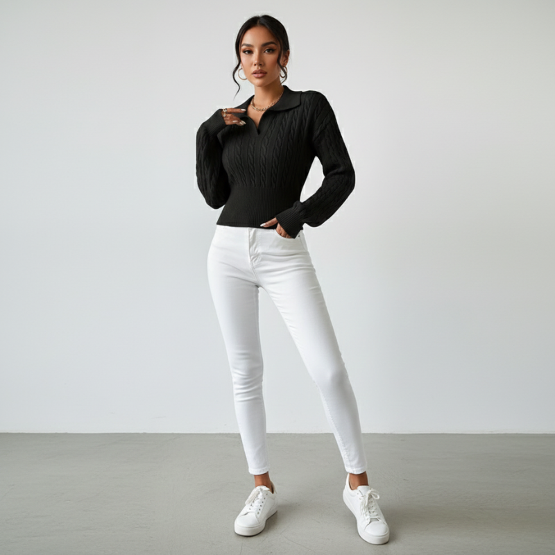 Model steht in schwarzem Pullover und weißer Hose, klare Silhouette in neutraler Studioaufnahme.